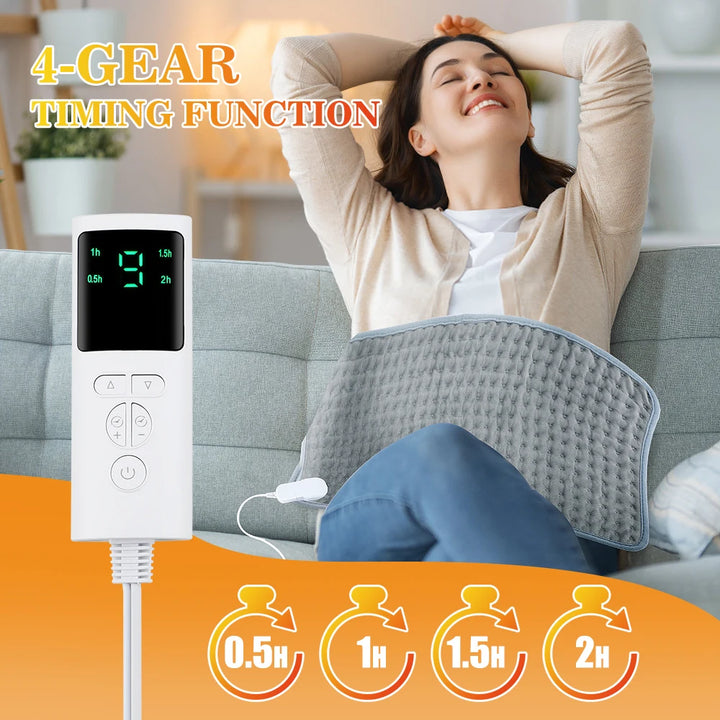 This image shows a woman sitting on a couch with the electric heating pad across her stomach, the white LCD display remote control with multiple buttons, and the four timer options of 0.5, 1, 1.5, and 2 hours