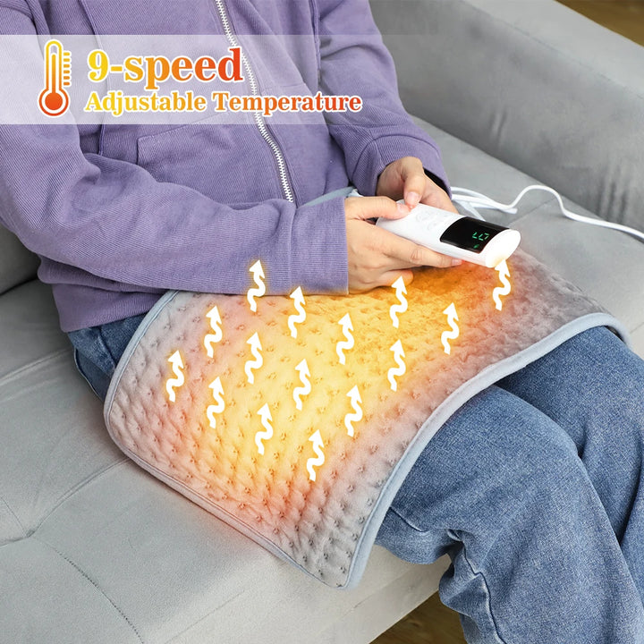 This image shows a person sitting on a couch with the electric heating pad on their lap with heat graphics rising from the pad. The person is holding the electric LCD remote control to operate and change the temperature level.