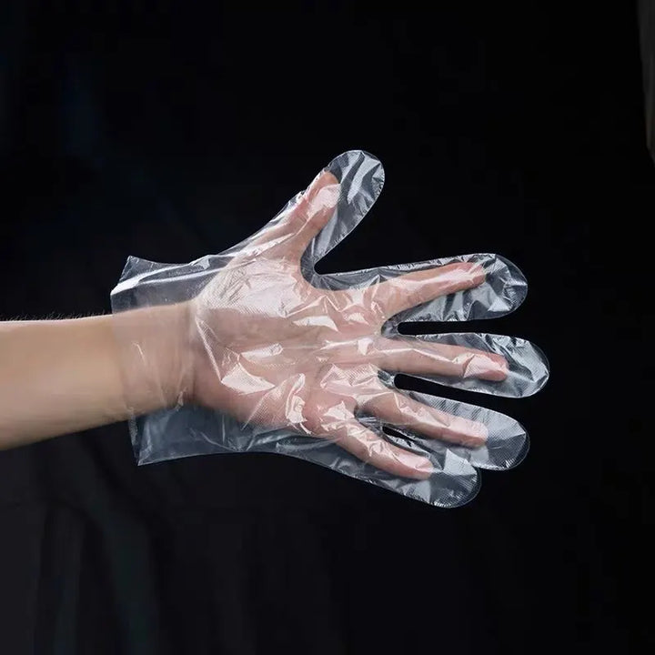 An image showing one clear disposable plastic glove on one hand of a man opening his palm wide on a black background