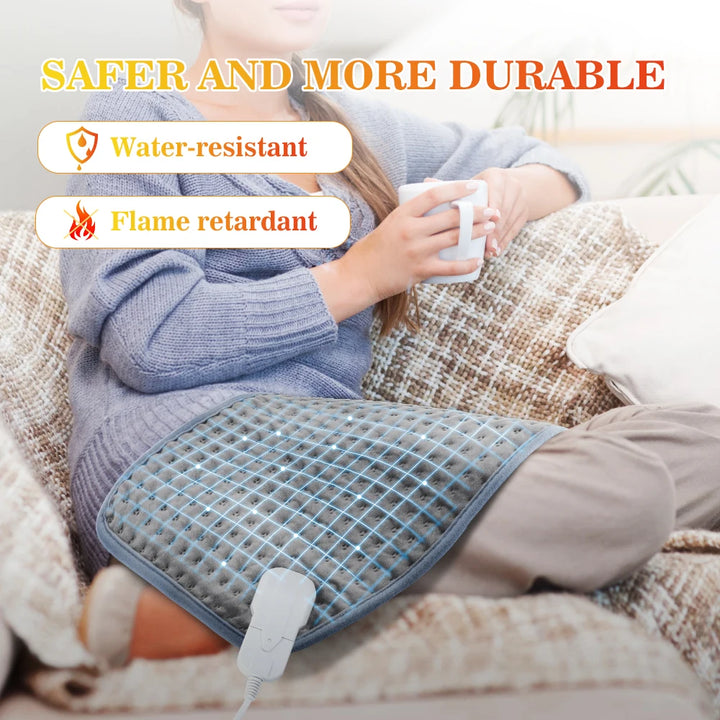This image shows a woman sitting on a couch holding a white mug with the electric heating pad draped across her lap with the features of water-resistant and flame retardant written as labels
