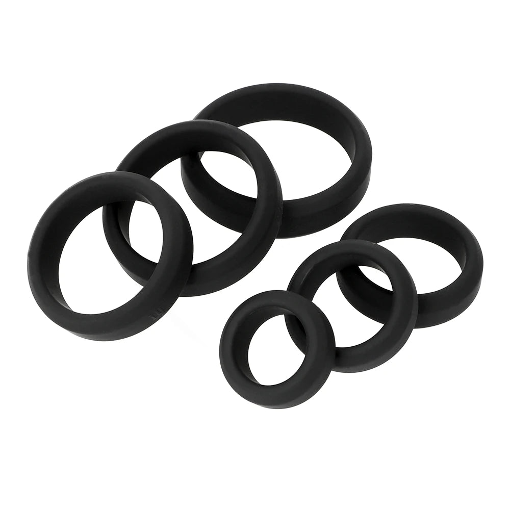 A set of six black flat cock ring bands of varying sizes made of synthetic silicone, displayed on a white background.