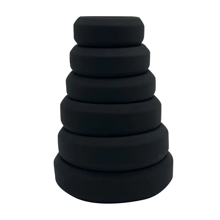 Full stack of six flat cock rings in black on a white background