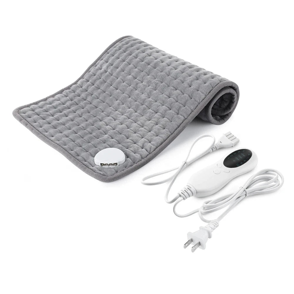 Image displaying a gray electric plush heating pad, half rolled up, next to the white electric LCD remote control