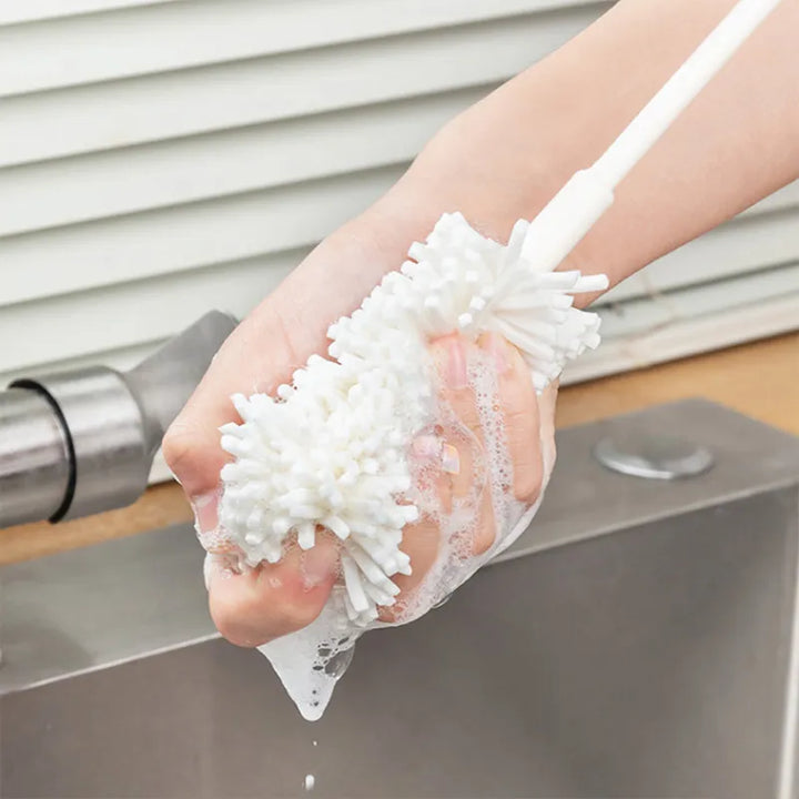 A graphic showing the polyester mop-like head of a penis pump cleaning brush being cleaned with soap and rubbed with someone's hand over a sink