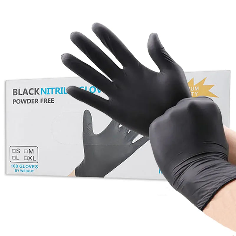 An image of a man putting on black nitrile gloves in front of the box of gloves