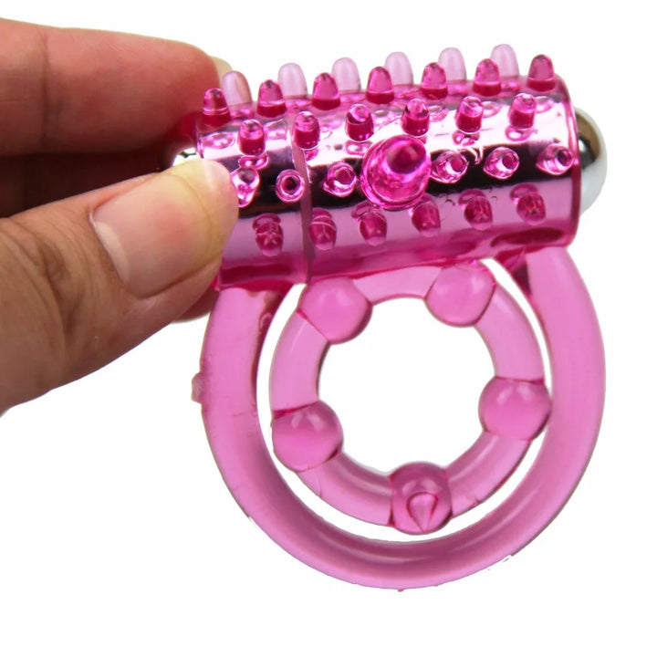 An image of a person holding a magenta transparent double-band cock ring with a stainless steel bullet vibrator inserted into the outer band that contacts the clitoris for stimulation