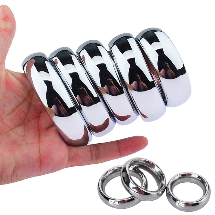 An image of a man holding a stack of five different sizes of premium stainless steel cock rings with three steel rings beneath
