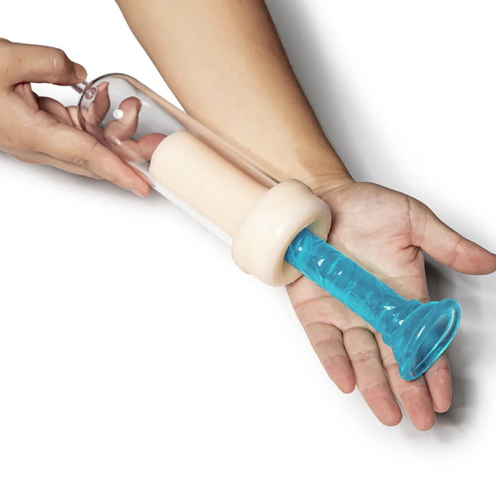 An image of a man holding a penis pump cylinder with the flesh like penis pump pleasure sleeve attached, inserting a dildo fake penis into the pleasure sleeve to show how it's used