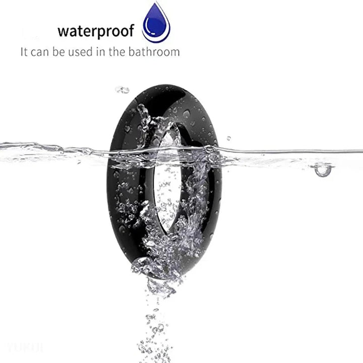 An image showing a black thick cylindrical cock ring being half submerged into water to show its waterproof properties