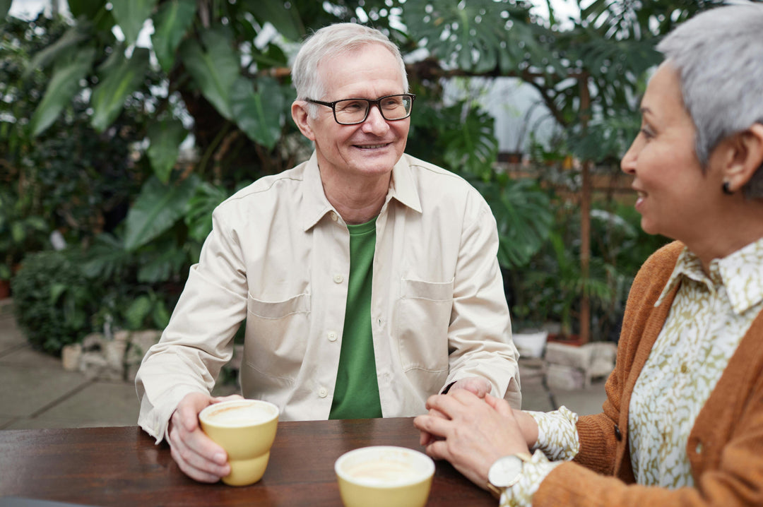 Old man with coffee sitting outdoors with wife having fun and happy conversation about sexual health goals