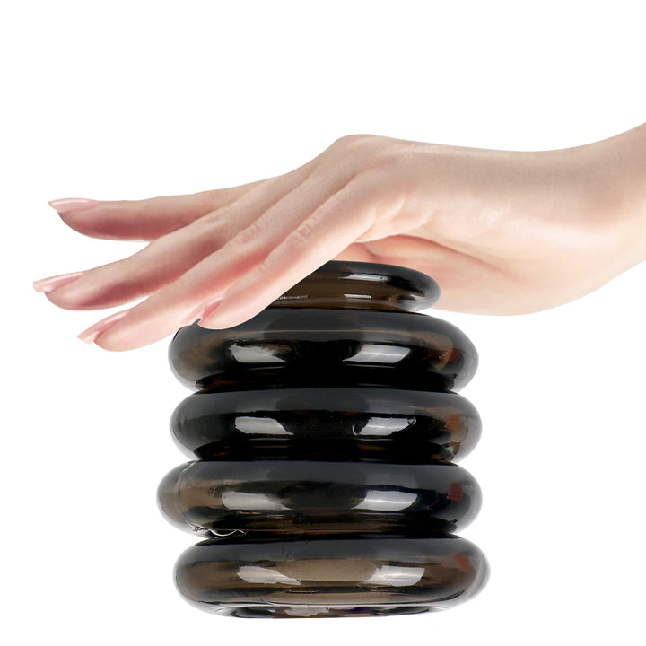An image showing a woman placing her hand over a stack of four black interlocking cock rings
