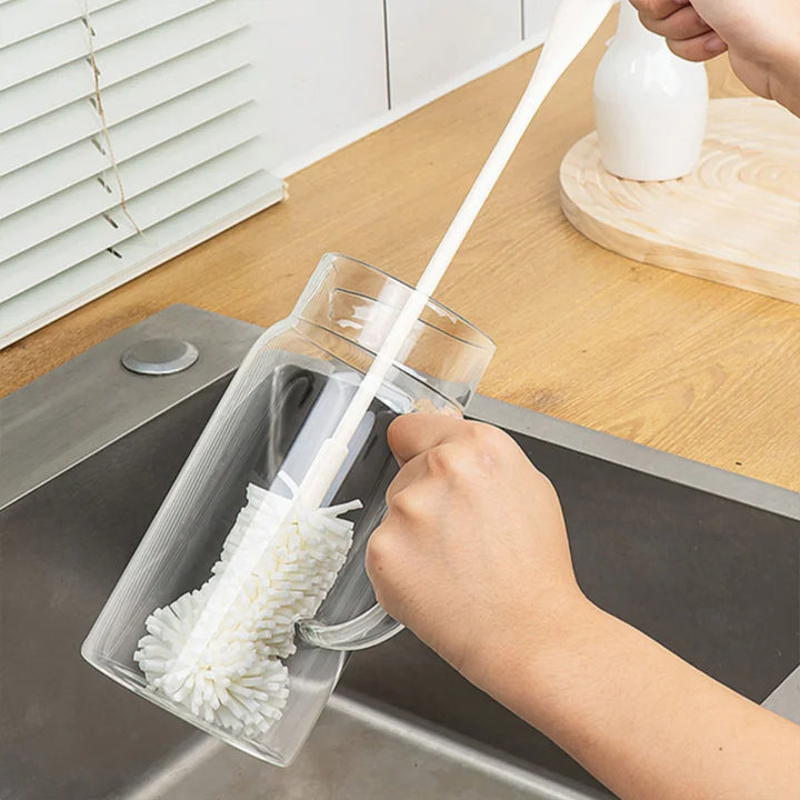 An image showing someone using the long polyester cleaning brush to clean the inside bottom of a bottle over a sink