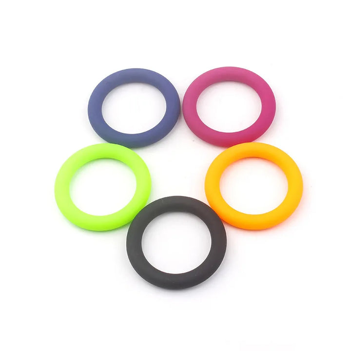 This photo shows five color coded cock rings, one of each of the five colors of black, blue, magenta, lime green, and tangerine orange