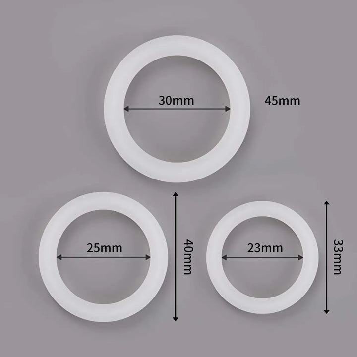 An image showing three white glow in the dark cock rings and their varying dimensions with large size measuring 30 mm internal diameter and 45 mm width, medium size with 25 mm internal diameter and 40 mm width, and small size measuring 23 mm internal diameter and 33 mm width