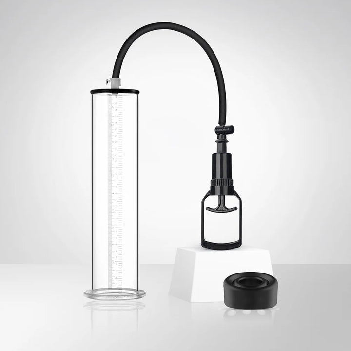 This photo shows a high-efficiency penis pump with a clear acrylic cylinder, black flexible long hose, and black manual handle lever on a white showcase block, with a black silicone sleeve
