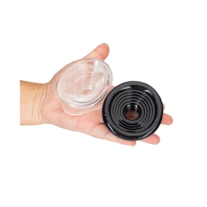 An image showing a clear and a black ribbed texture penis pump sleeve cover in a man's hand on a white background
