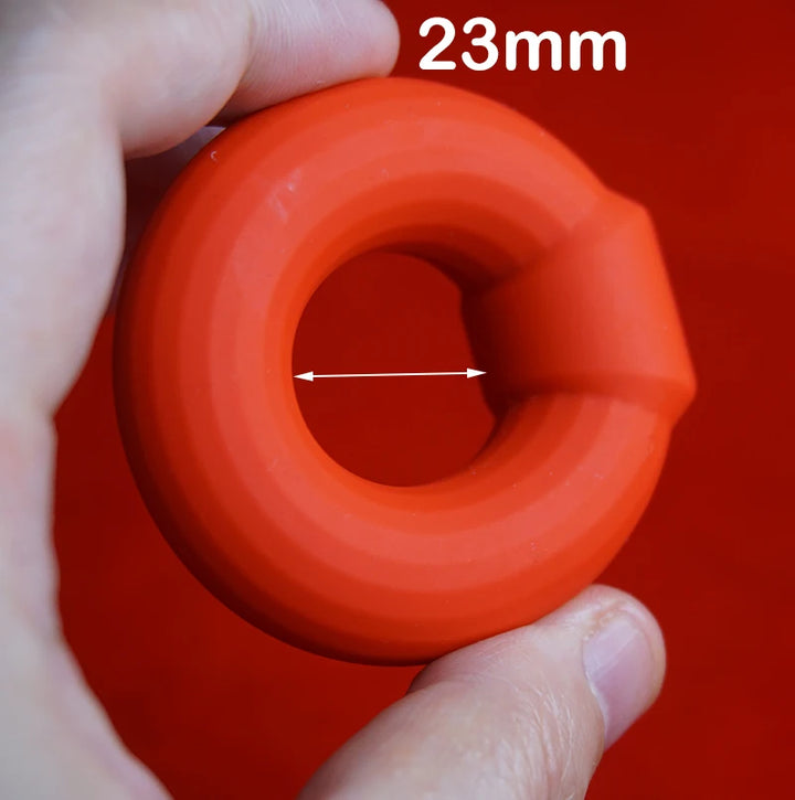 Red cylindrical cock ring with a hole, held by a hand, against a red background with '23mm' text.