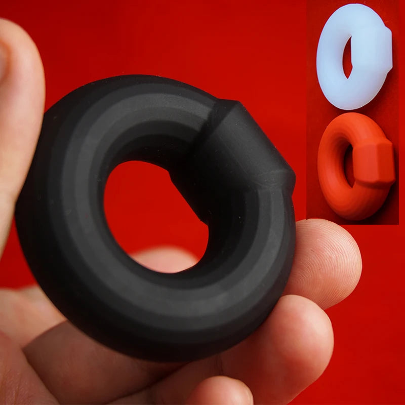 Black silicone rubber constriction ring held in a man's hand with red background with two other rings of white and red colors in the background.