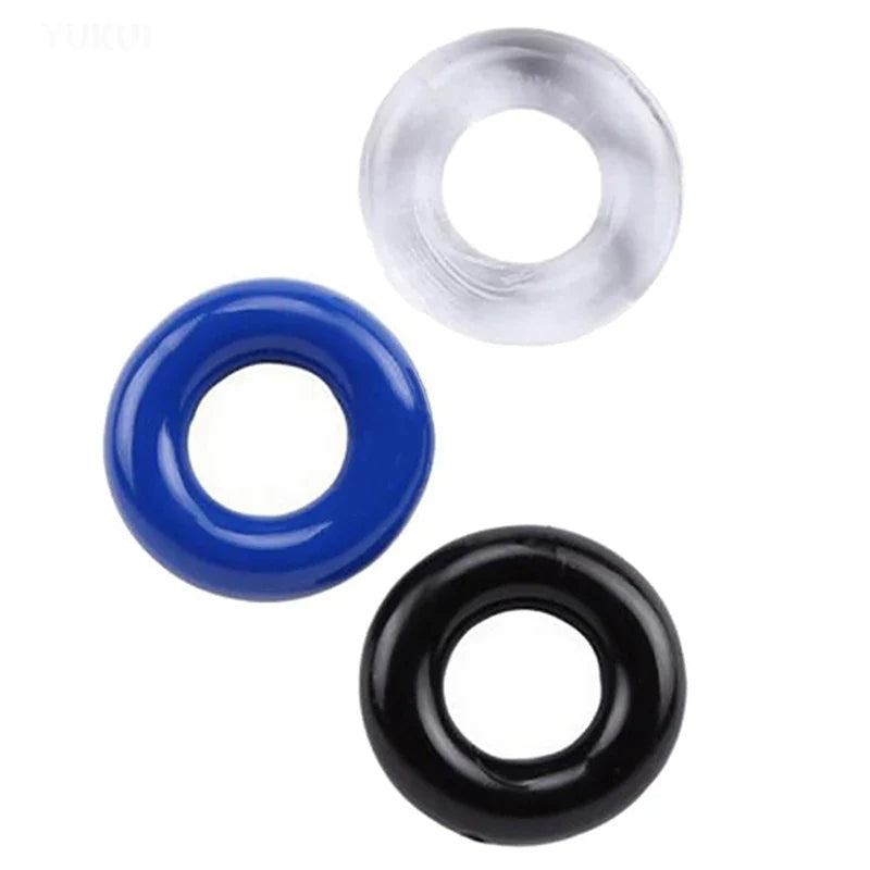An image showing three thick cylindrical cock rings in clear/white, opaque blue, and opaque black, made of silicone material on a white background