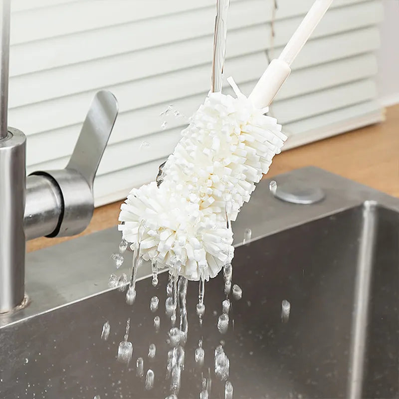 An image showing the mop-like head of the pump cleaning brush being cleaning off under running water with droplets running off the head to show its waterproof material