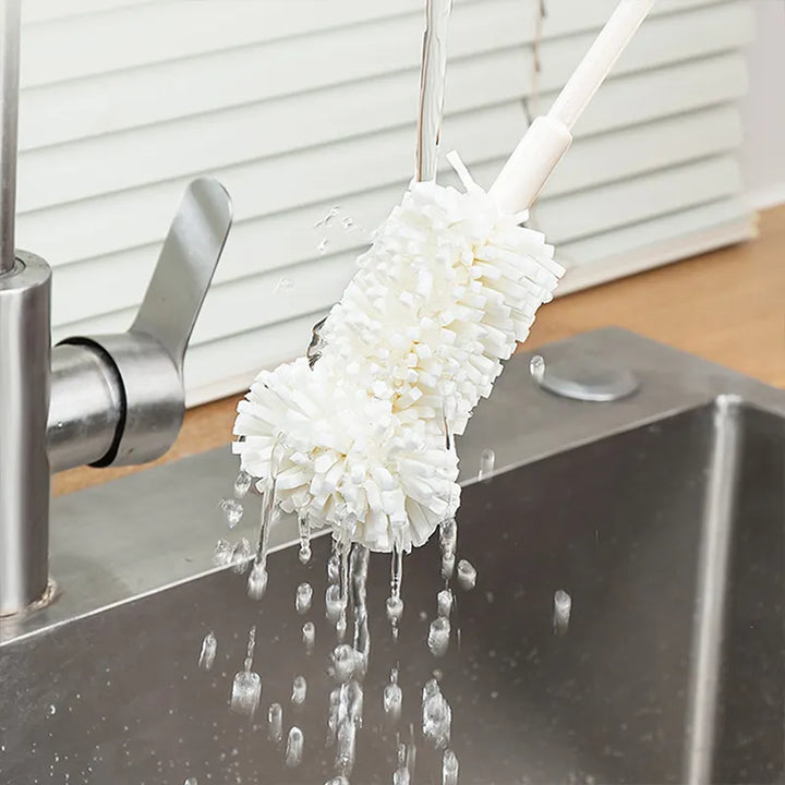 An image showing the mop-like head of the pump cleaning brush being cleaning off under running water with droplets running off the head to show its waterproof material